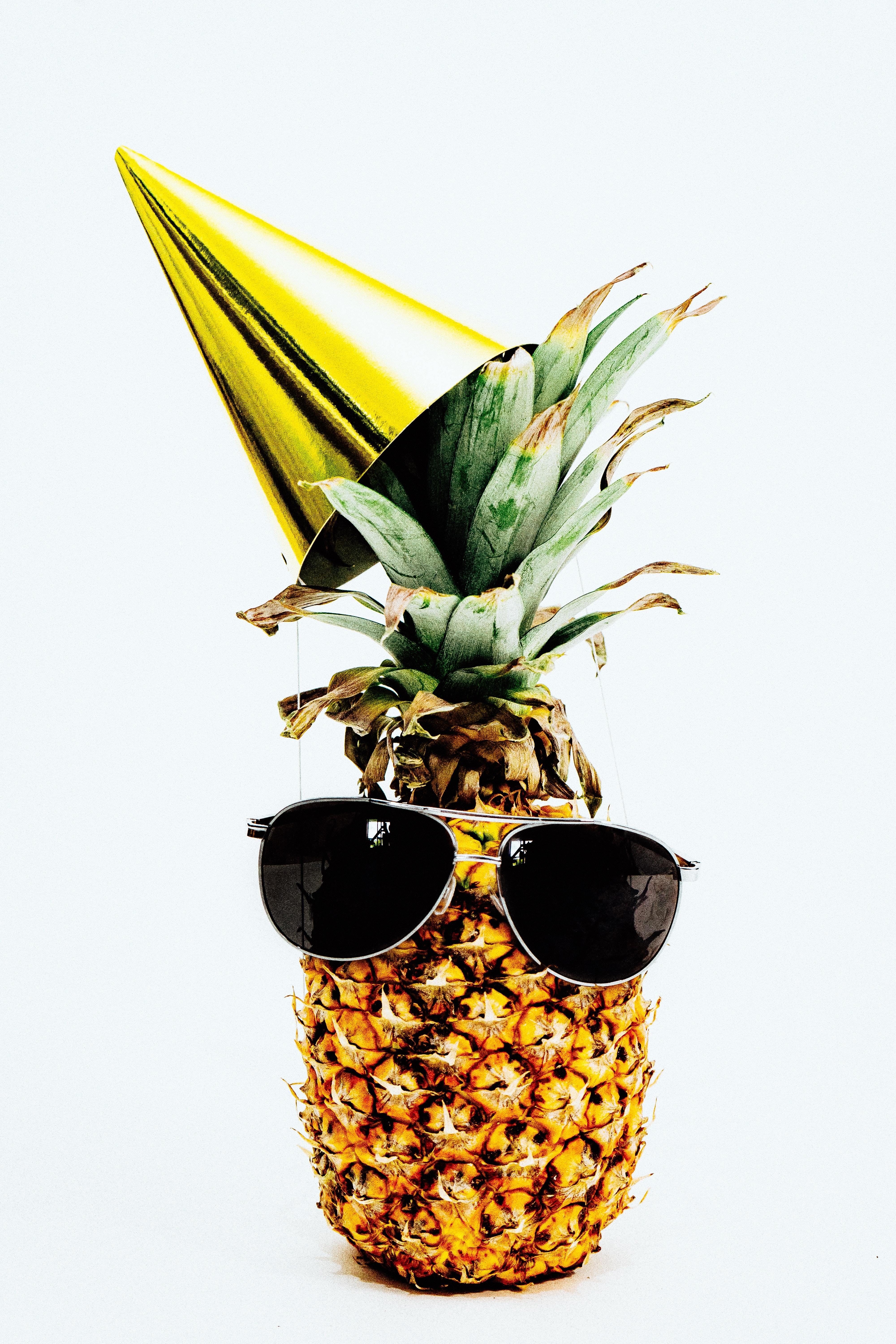Pineapple wearing aviator shades and a shiny gold party hat