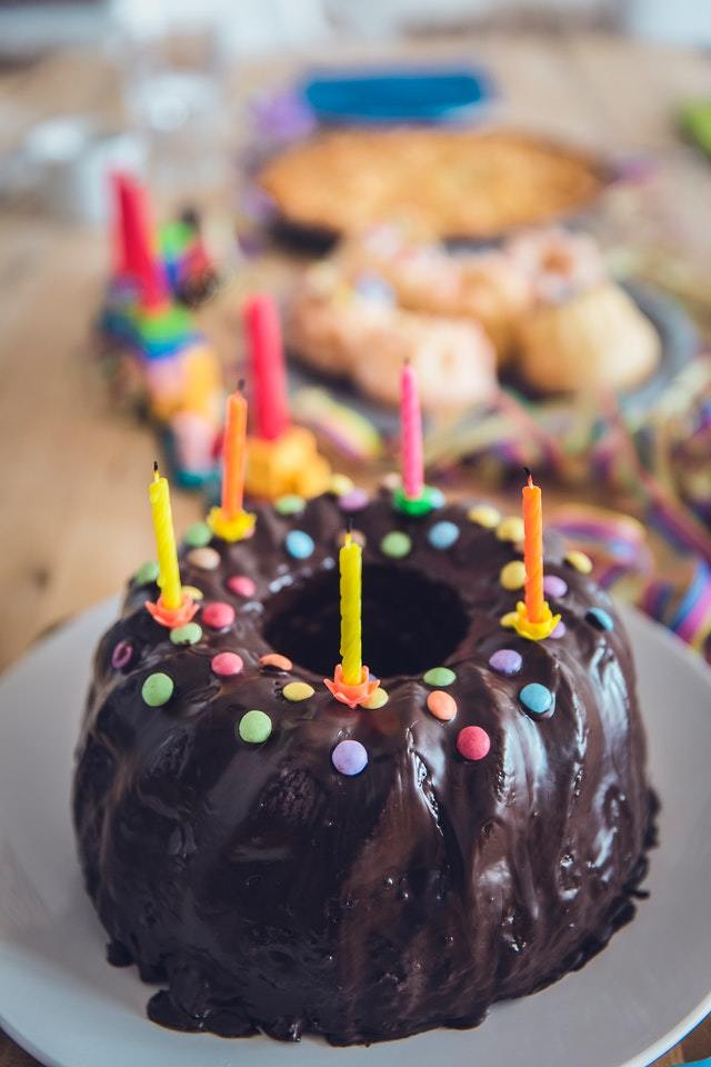 Chocolate ring cake with birthday candles and brightly colored candies